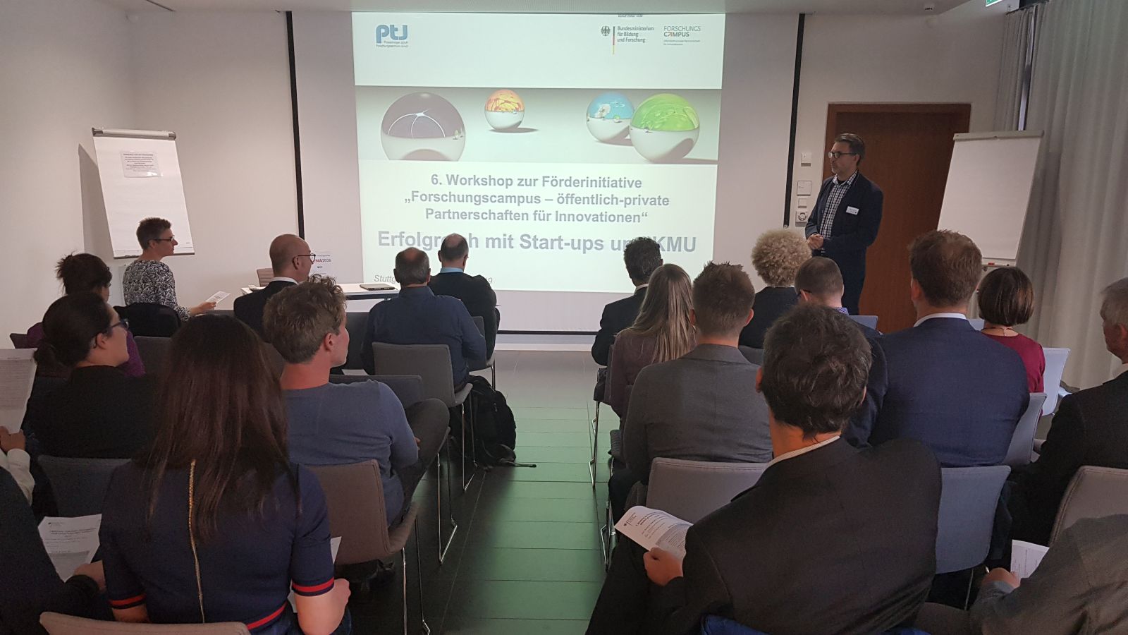 Publikum von hinten mit Blick auf Präsentation